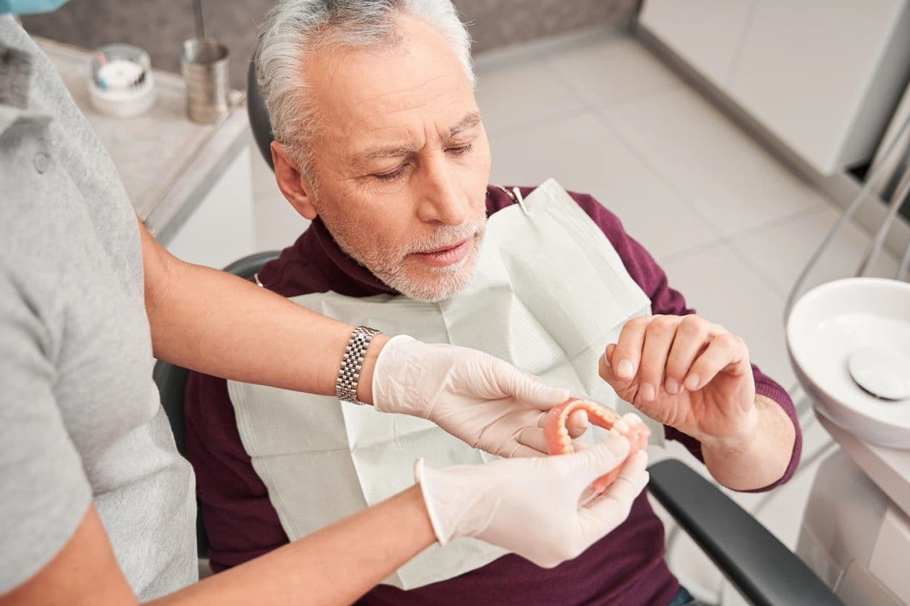 Photo of a patient being shown upper and lower arch dentures
