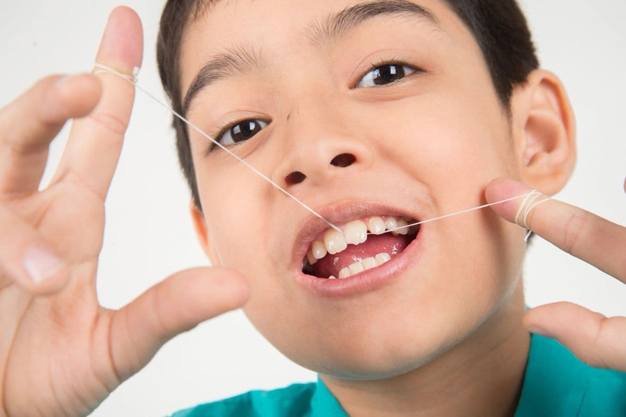 A photo of a young boy flossing his teeth.