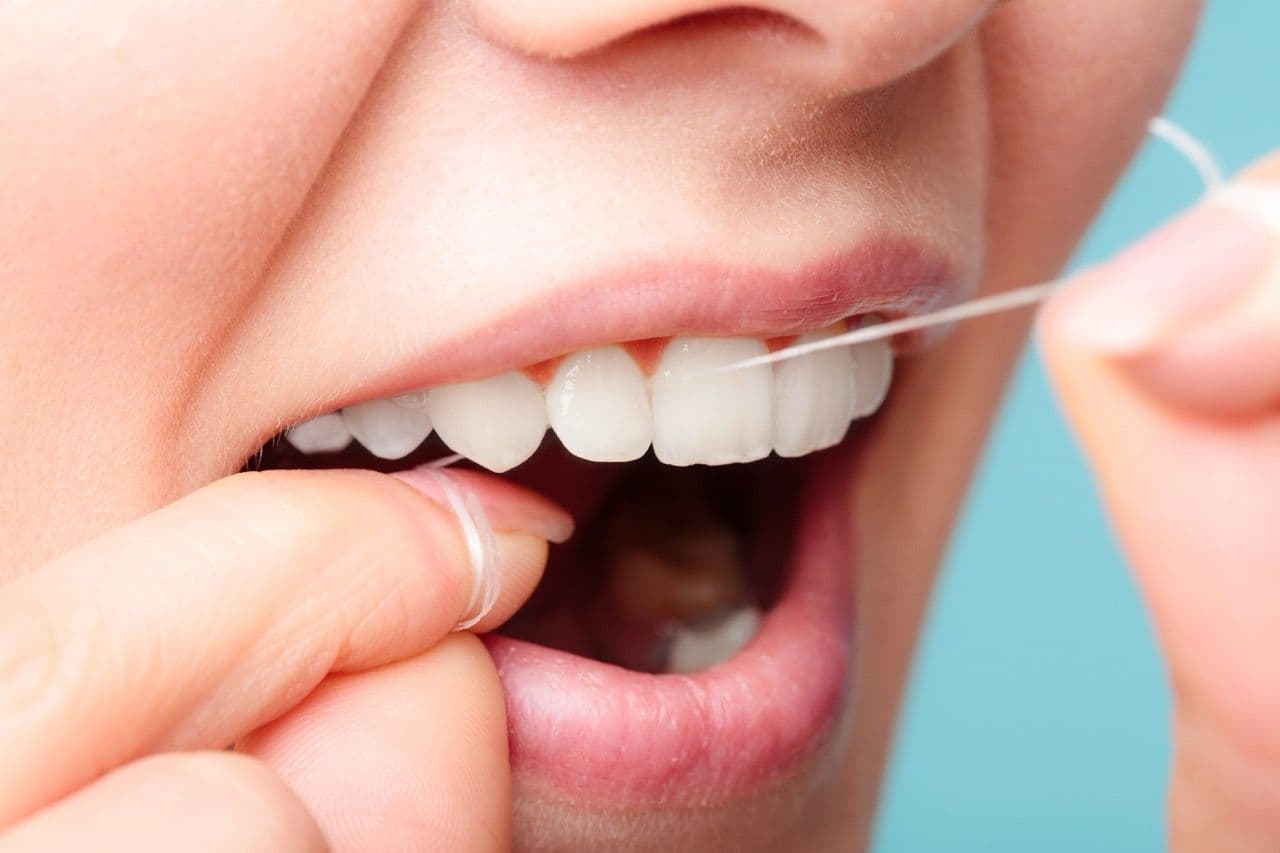 Close-up photo of a mouth in the process of flossing.