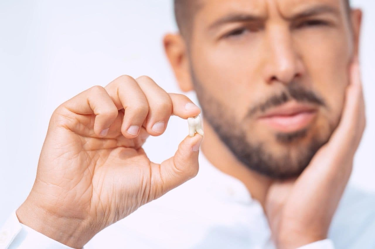 Photo of a man holding up a tooth