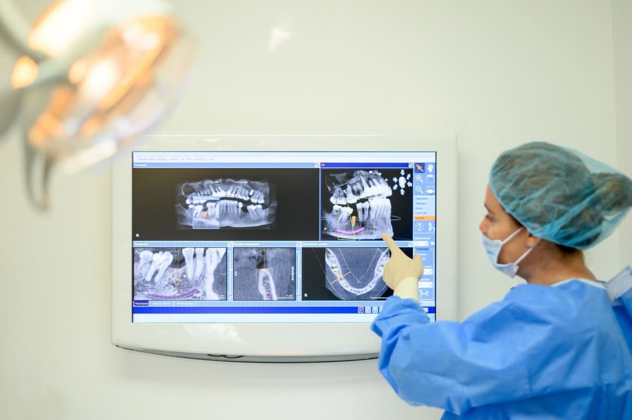 A photo of a dentist pointing at X-rays.