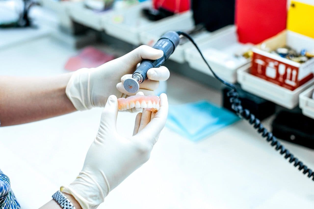 Photo of a lab technician's hands as they sculpt a denture